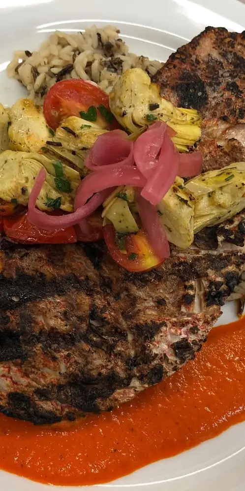 Grilled genuine American red snapper filet, herb roasted artichoke hearts and grape tomatoes. Served
